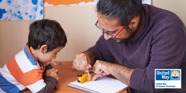 Image of a father showing his son how to trace objects.
