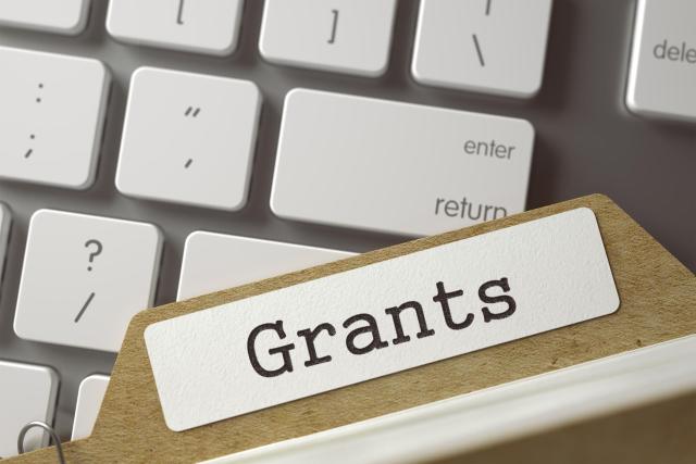 File folder labeled "grants" resting on a keyboard