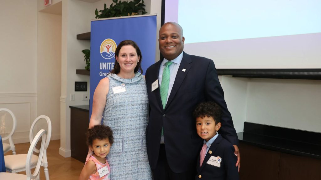 Four people standing together in a room with a banner on the left side that reads 'United Way of Greater Cincinnati.'
