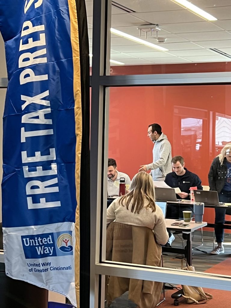 People working at laptops inside a room with a large banner reading “Free Tax Prep Site” from United Way of Greater Cincinnati.